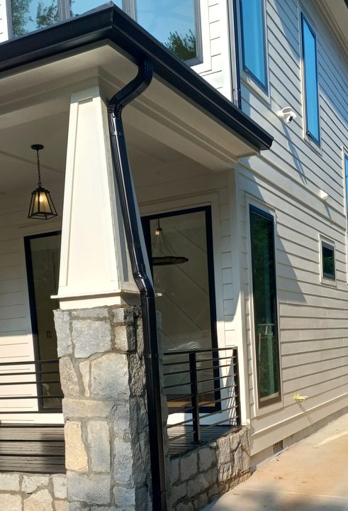 A real Smitty black downspout fitted along a white porch column