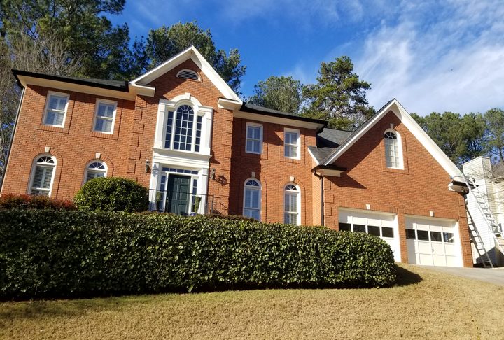 Orange brick colonial with dark gutters over a two-car garage