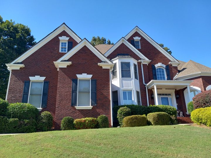 Large red brick traditional home with white gutters and downspouts