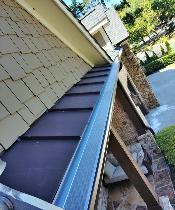 Gutter with a micro-mesh guard along a bronze metal porch roof