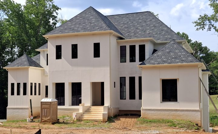 Front of a new cream stucco home with matching cream gutters