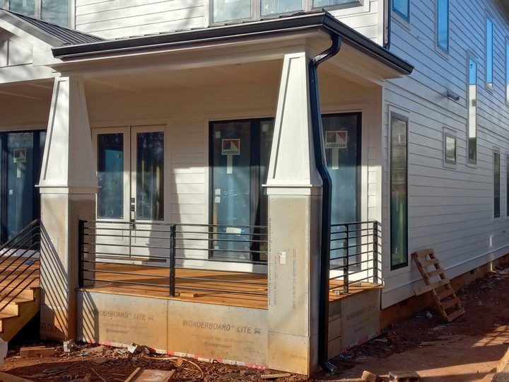 Black gutter and downspout on the porch of a new-construction farmhouse
