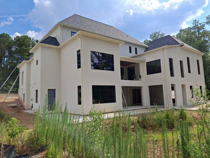 Rear of a three-story new build with cream gutters and downspouts