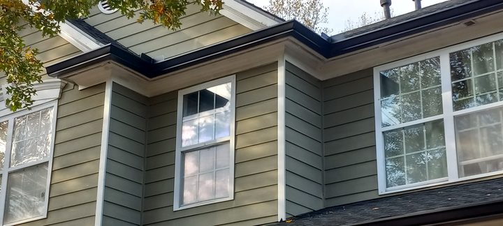 Dark bronze gutters following the complex roofline of a sage fiber-cement home