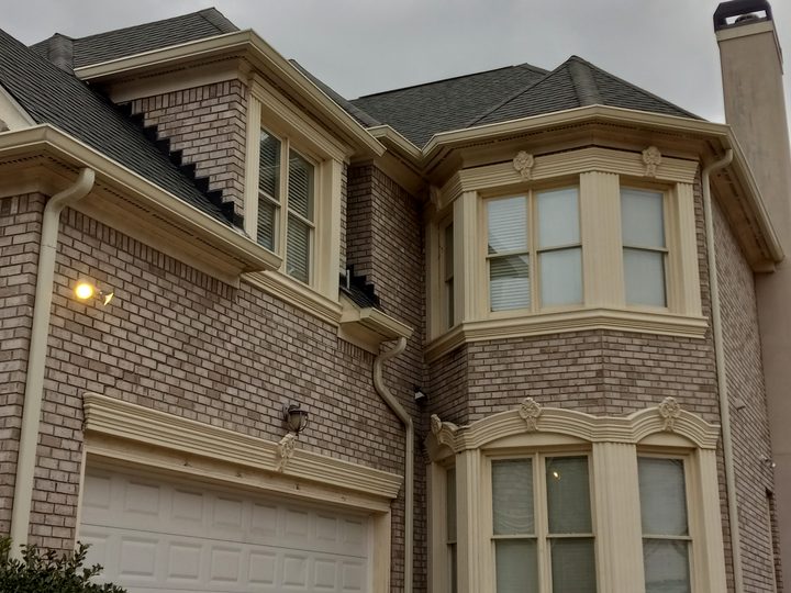 Tan brick home with almond gutters and several matching downspouts